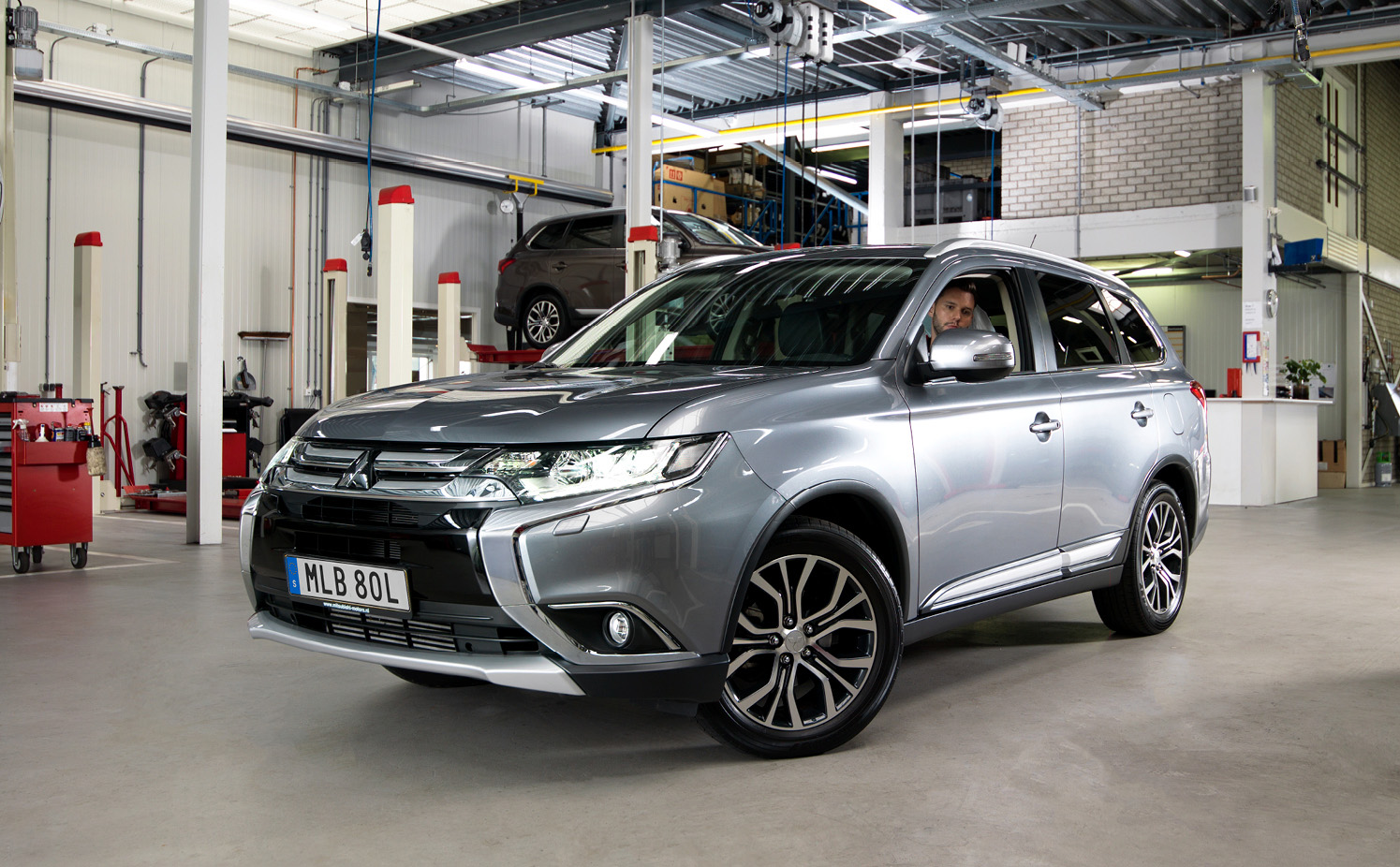 Vit Mitsubishi Eclipse Cross kör på väg genom solig skog