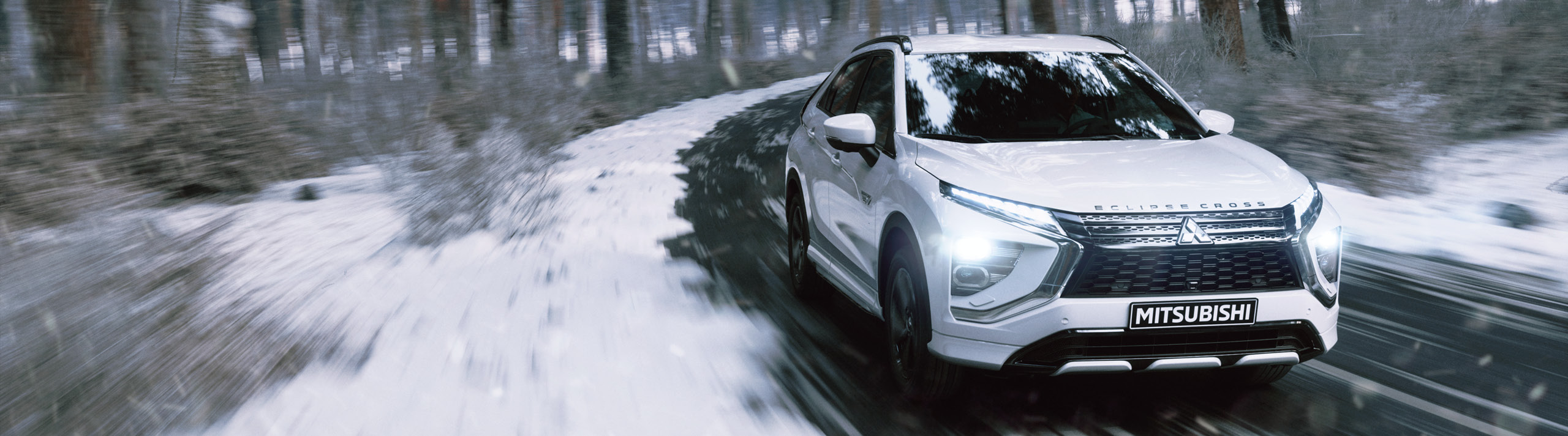 okt_hjulskifte_se_2560x713 En Mitsubishi Eclipse Cross kör igenom en snöig skog