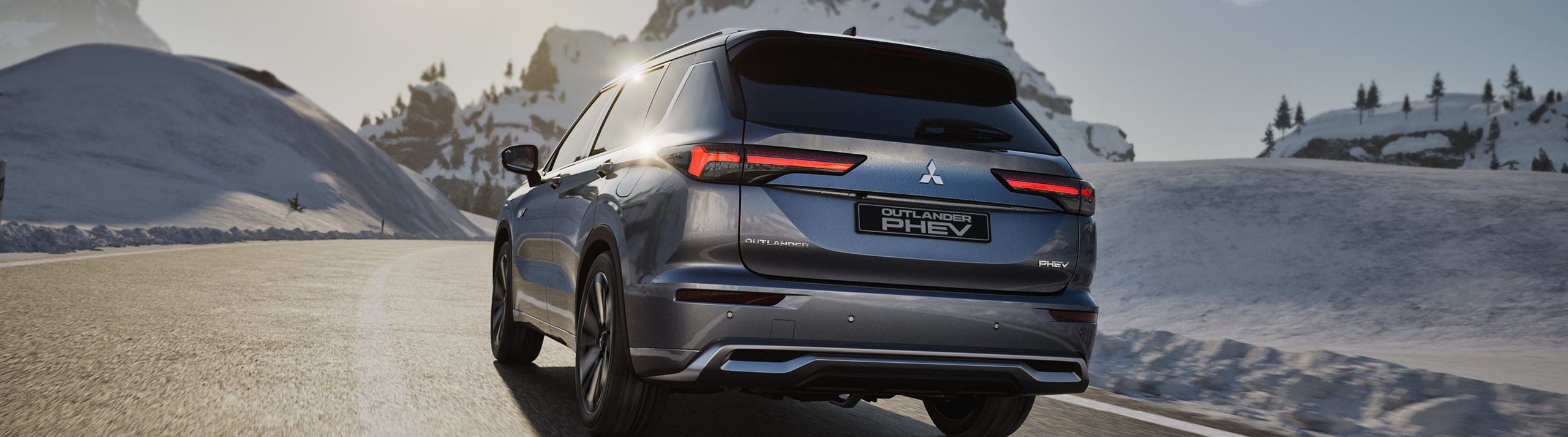 okt_hjulskifte_se_2560x713 Mitsubishi Outlander kör på en asfalterad väg med berg och snö i bakgrunden