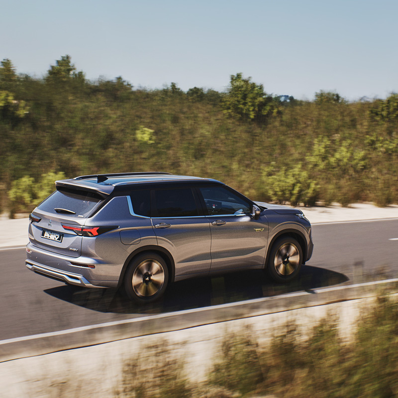 Mitsubishi Outlander kör på en asfalterad väg med berg och snö i bakgrunden