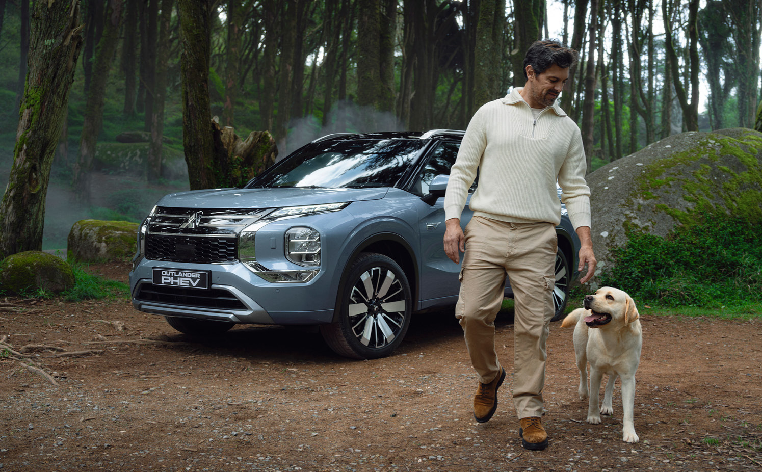 En man med en hund går framför en Mitsubishi Outlander